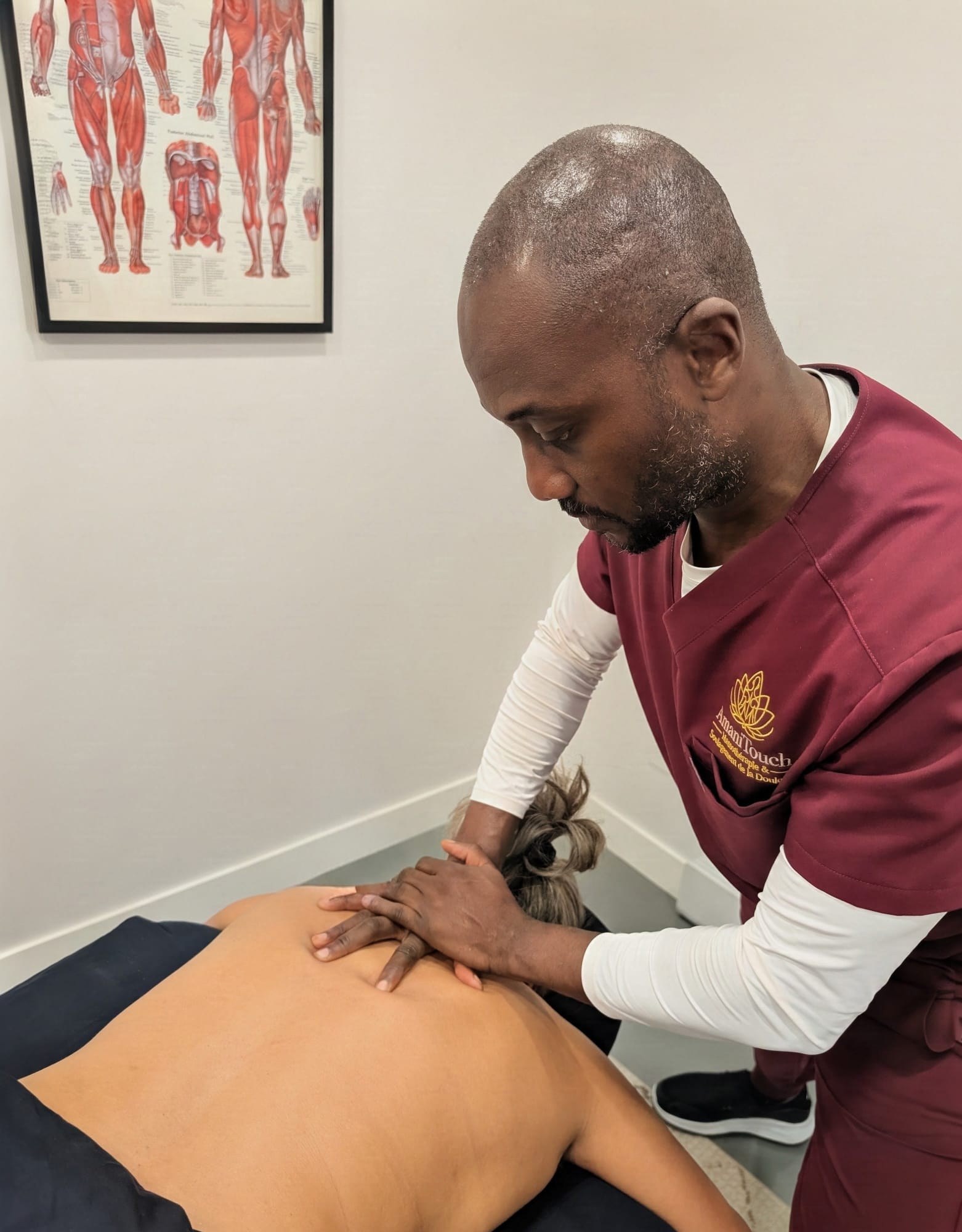 Massothérapeute d’AmaniTouch effectuant un massage thérapeutique des tissus profonds dans le haut du dos d’une personne.
